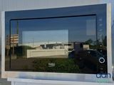 a reflection of a building in the window of a microwave oven