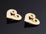 une paire de boucles d'oreilles en or en forme de cœur posées sur une surface noire
