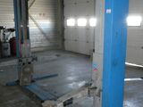 un garage avec un pont élévateur bleu au milieu