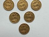 six british gold sovereigns on a white surface