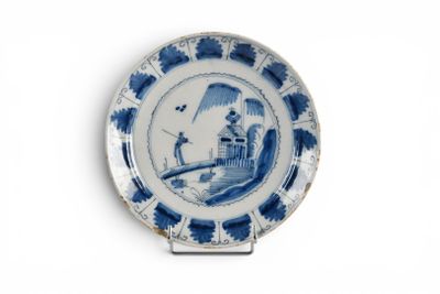 une assiette bleue et blanche sur laquelle est représenté un homme sur un pont