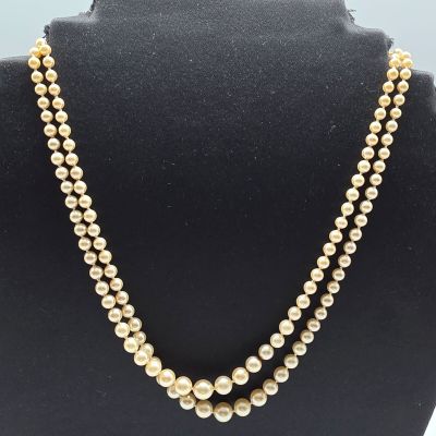 two strand pearl necklace with gold beads on a black mannequin