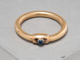 gros plan d'une bague en or avec une pierre bleue