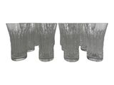 four clear glass vases are lined up on a white surface