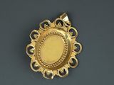 an image of a gold plated pendant on a black surface