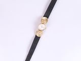 gros plan d'une montre sur une surface blanche avec un bracelet noir