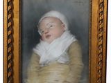 portrait d'un bébé portant un foulard blanc, dans un cadre doré