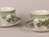 two green and white cups and saucers on a white surface