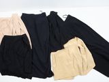 trois paires de pantalons noirs, beiges et beiges posées sur une surface blanche