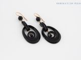 a pair of black and gold earrings on a white surface