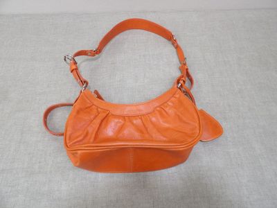 un sac à main orange posé sur une surface blanche