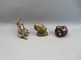 three small bronze figurines of animals on a white surface