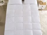 a close up of a bed with a white comforter on top of it
