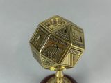 a close up of a gold and red object on a white surface