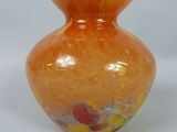 un vase orange posé sur une surface blanche