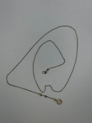 a close up of a necklace on a white surface with a chain