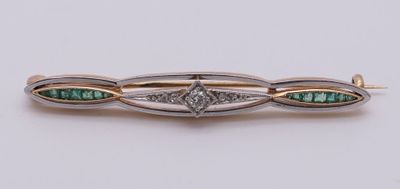 a close up of a diamond and emerald broochle on a white surface