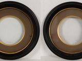 pair of black and gold oval picture frames on a white wall