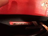 someone is holding a red purse with a tag on it
