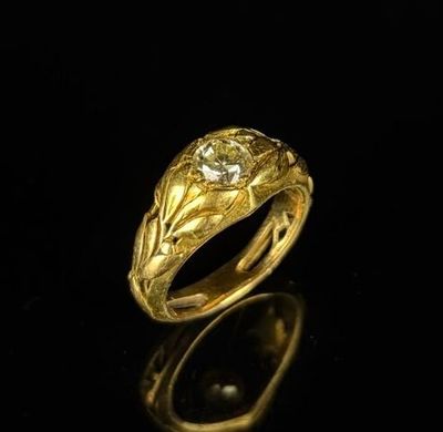 gros plan d'une bague en or avec un diamant au centre