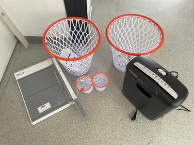 deux poubelles et une déchiqueteuse à papier posées par terre