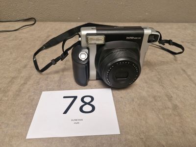 a black and silver camera sitting on a table next to a sign