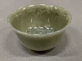 a green bowl sitting on a table with water in it