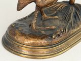 a bronze statue of a bird sitting on top of a base