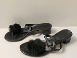 pair of black sandals with pom poms on them sitting on a white surface