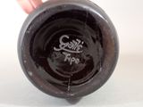 a person holding a brown vase with a black lid