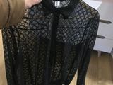 a person holding a black shirt on a hanger in a room