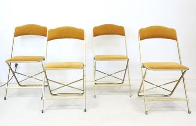 quatre chaises pliantes disposées côte à côte sur un sol blanc