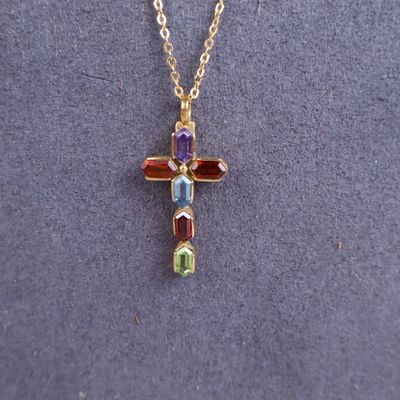 a gold cross necklace with multi colored stones on a gold chain