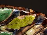 a close up of a decorative vase with leaves on it