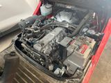a red car with a silver engine and a white car in the background