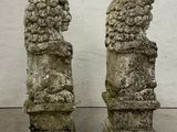 pair of stone lions on pedestals in front of a white wall