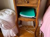 a small table with a lamp on top of it next to a bed