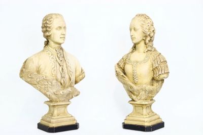une paire de bustes sculptés représentant un homme et une femme, posés sur des socles en marbre