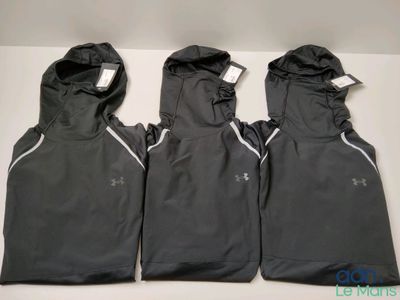 Trois gilets Under Armour pour homme sont alignés sur une table