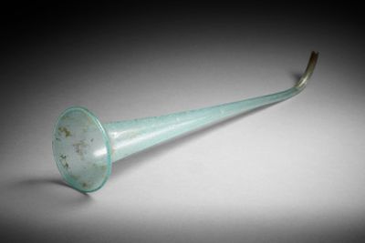 un objet en verre vert en forme de trompette posé sur une table