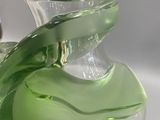 a green glass vase sitting on a white surface