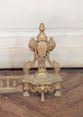 une horloge dorée posée sur un parquet, à côté d'une porte blanche
