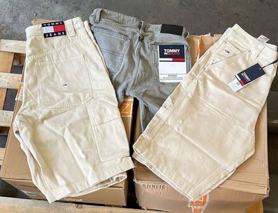 trois paires de pantalons pour homme posées sur des cartons dans un entrepôt