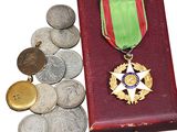 des pièces et une médaille se trouvent dans une boîte rouge ornée d'un ruban vert