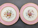 two pink plates with gold trims and flowers on them