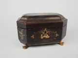 an old black and gold box sitting on top of a white surface