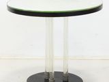 a round glass table with a black base and a green top