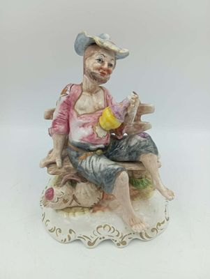 figurine en porcelaine représentant un homme assis sur un banc, tenant un oiseau dans la main