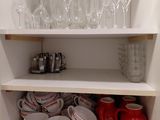 many cups and glasses on a shelf in the kitchen