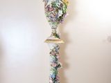 a tall vase with a bird on top of it